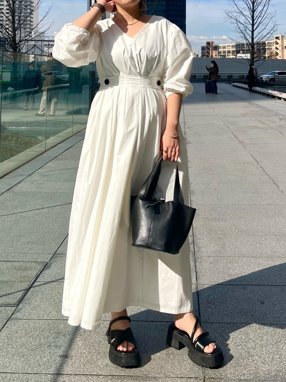 ブラック系のサンダル、ホワイト系のワンピース、ブラック系のハンドバッグを着用したレディースの冬コーディネートの1枚目の写真