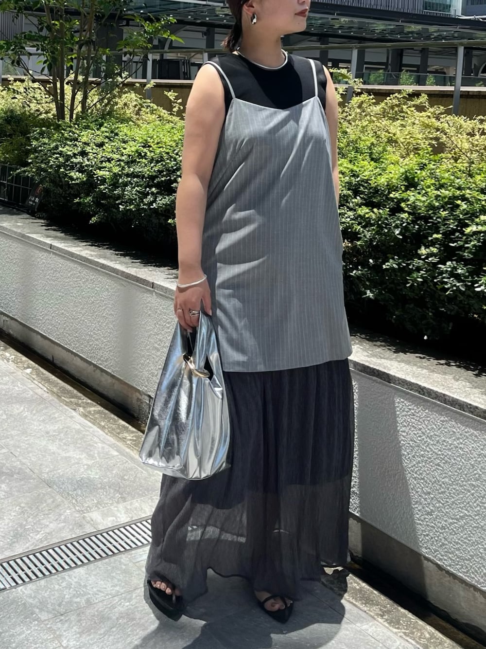 ブラック系のニット/セーター、グレー系のワンピース、シルバー系のハンドバッグを着用したレディースの夏コーディネートの1枚目の写真