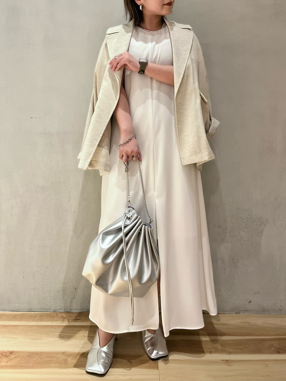 ベージュ系のテーラードジャケット、ホワイト系のワンピース、シルバー系のショルダーバッグを着用したレディースの春コーディネートの1枚目の写真