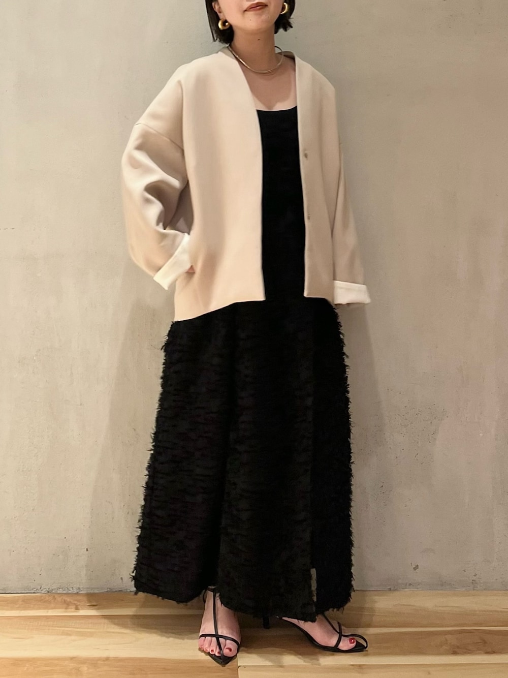 ブラック系のワンピース、ブラック系のタンクトップ、ベージュ系のノーカラーコートを着用したレディースの春コーディネートの1枚目の写真