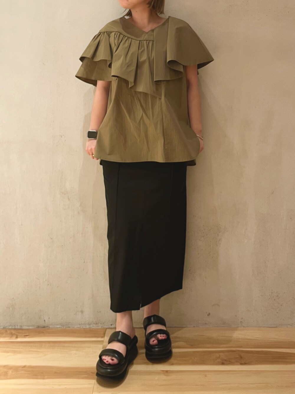 グリーン系のシャツ/ブラウス、ブラック系のスカート、ブラック系のサンダルを着用したレディースの冬コーディネートの1枚目の写真