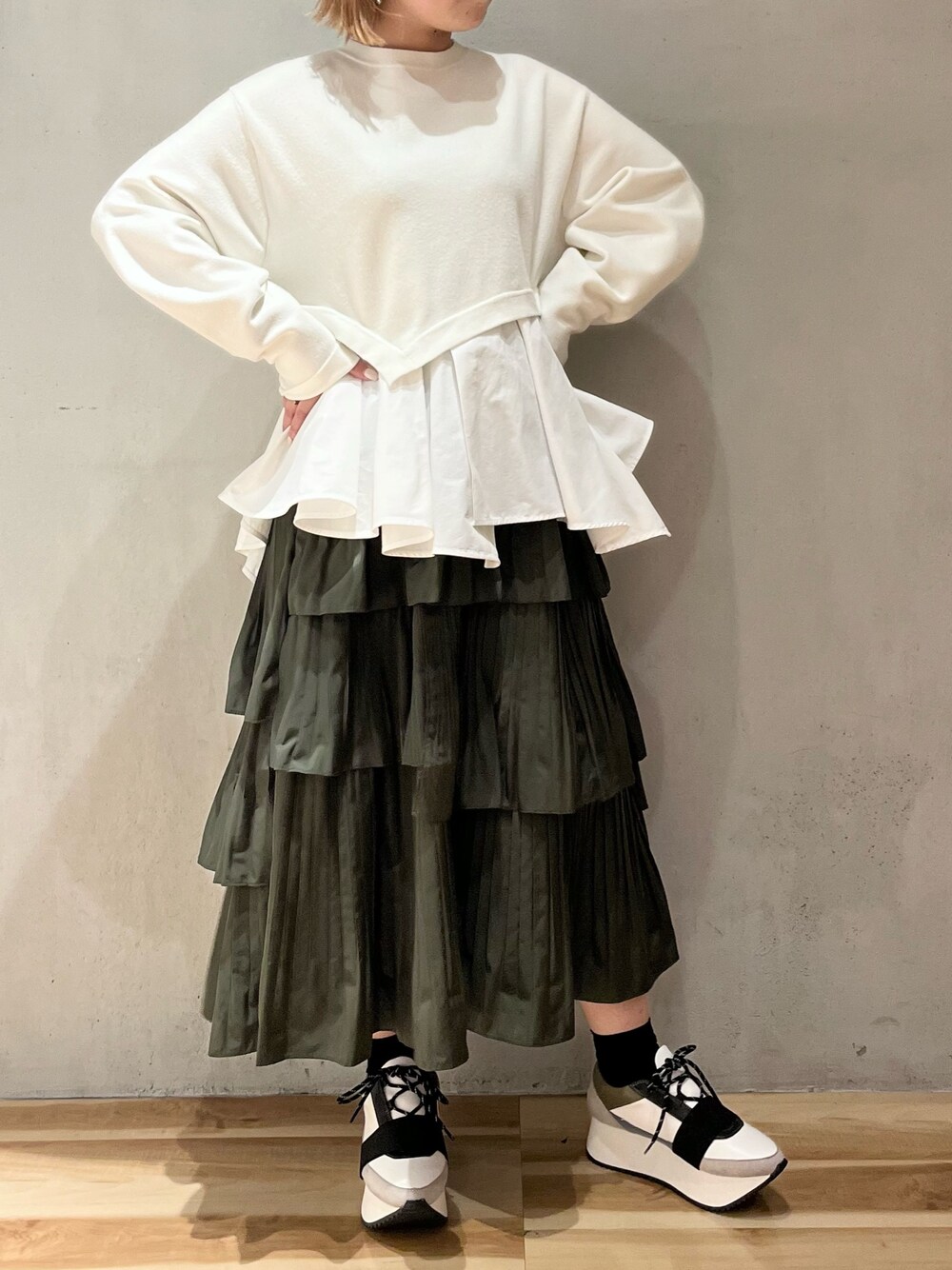 ホワイト系のニット/セーター、ベージュ系のスカート、ブルー系のスニーカーを着用したレディースの秋コーディネートの1枚目の写真