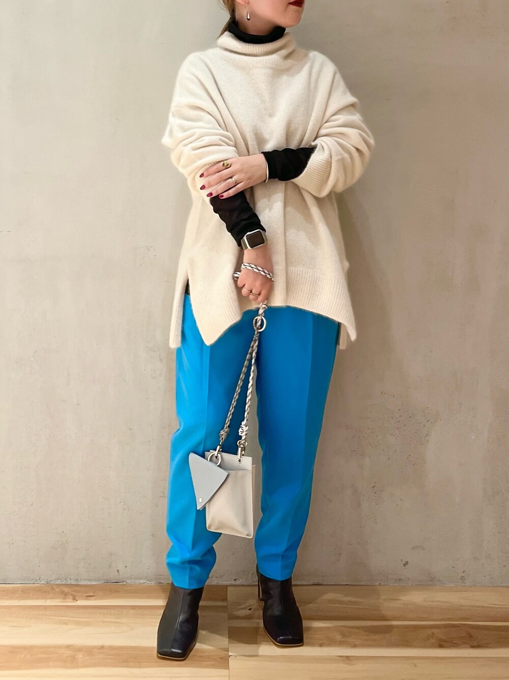 ブラック系のブーツ、ブラック系のTシャツ/カットソー、ホワイト系のニット/セーターを着用したレディースの冬コーディネートの1枚目の写真