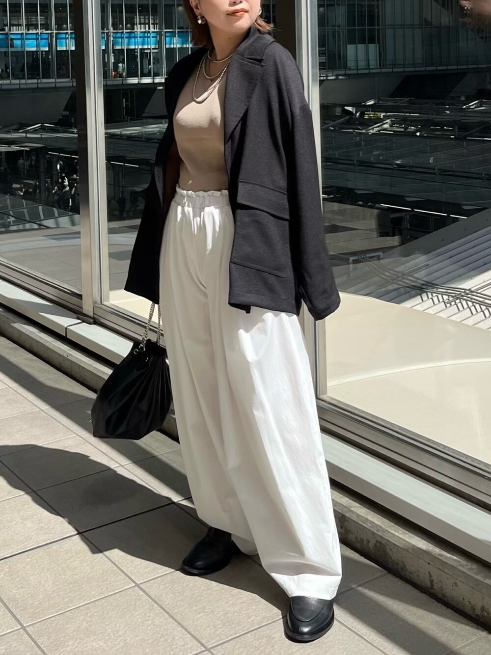 ブラック系のテーラードジャケット、ベージュ系のニット/セーター、ホワイト系のその他パンツを着用したレディースの春コーディネートの1枚目の写真