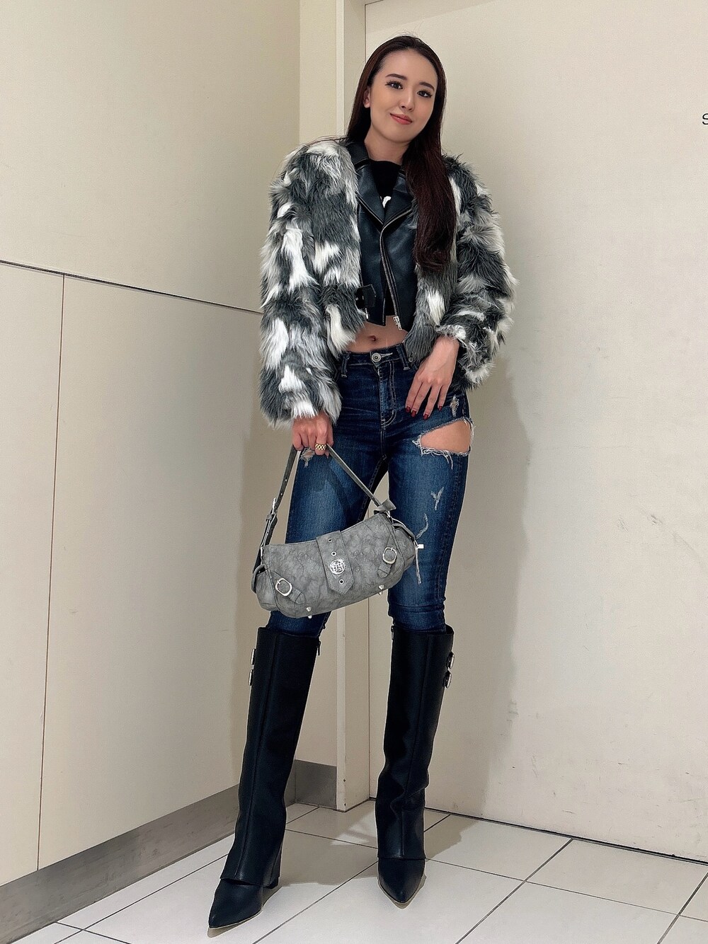 ブルー系のデニムパンツ、ブラック系のブーツ、グリーン系のショルダーバッグを着用したレディースの秋コーディネートの1枚目の写真