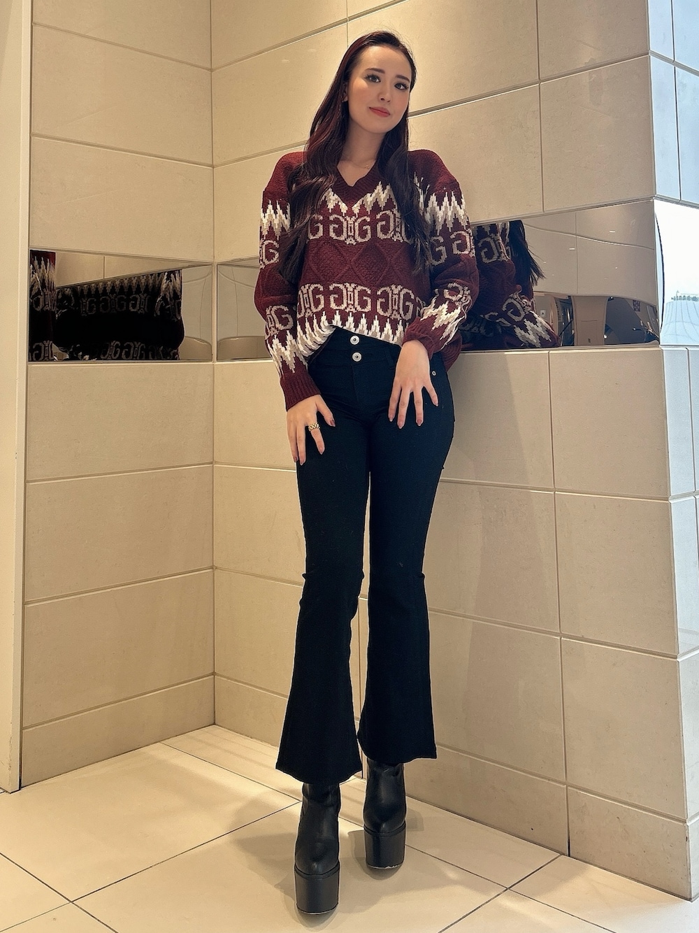 レッド系のニット/セーター、ブラック系のデニムパンツ、ブラック系のブーツを着用したレディースの冬コーディネートの1枚目の写真