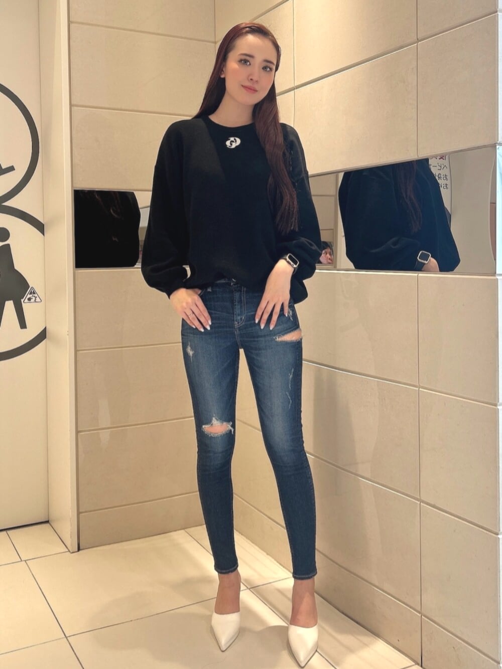 ブルー系のデニムパンツ、ホワイト系のパンプス、ブラック系のニット/セーターを着用したレディースの冬コーディネートの1枚目の写真