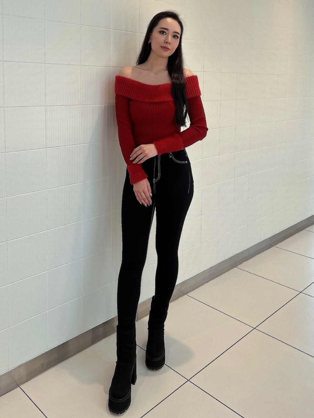 レッド系のニット/セーター、ブルー系のデニムパンツ、ブラック系のブーツを着用したレディースの冬コーディネートの1枚目の写真