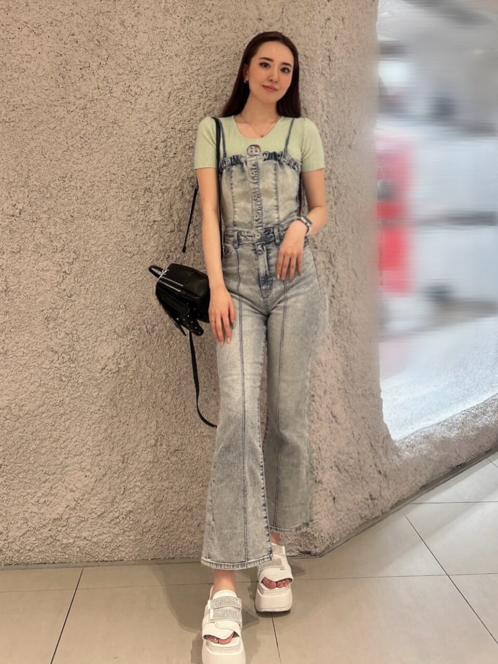 グリーン系のニット/セーター、ブルー系のつなぎ/オールインワン、ブラック系のバックパック/リュックを着用したレディースの春コーディネートの1枚目の写真