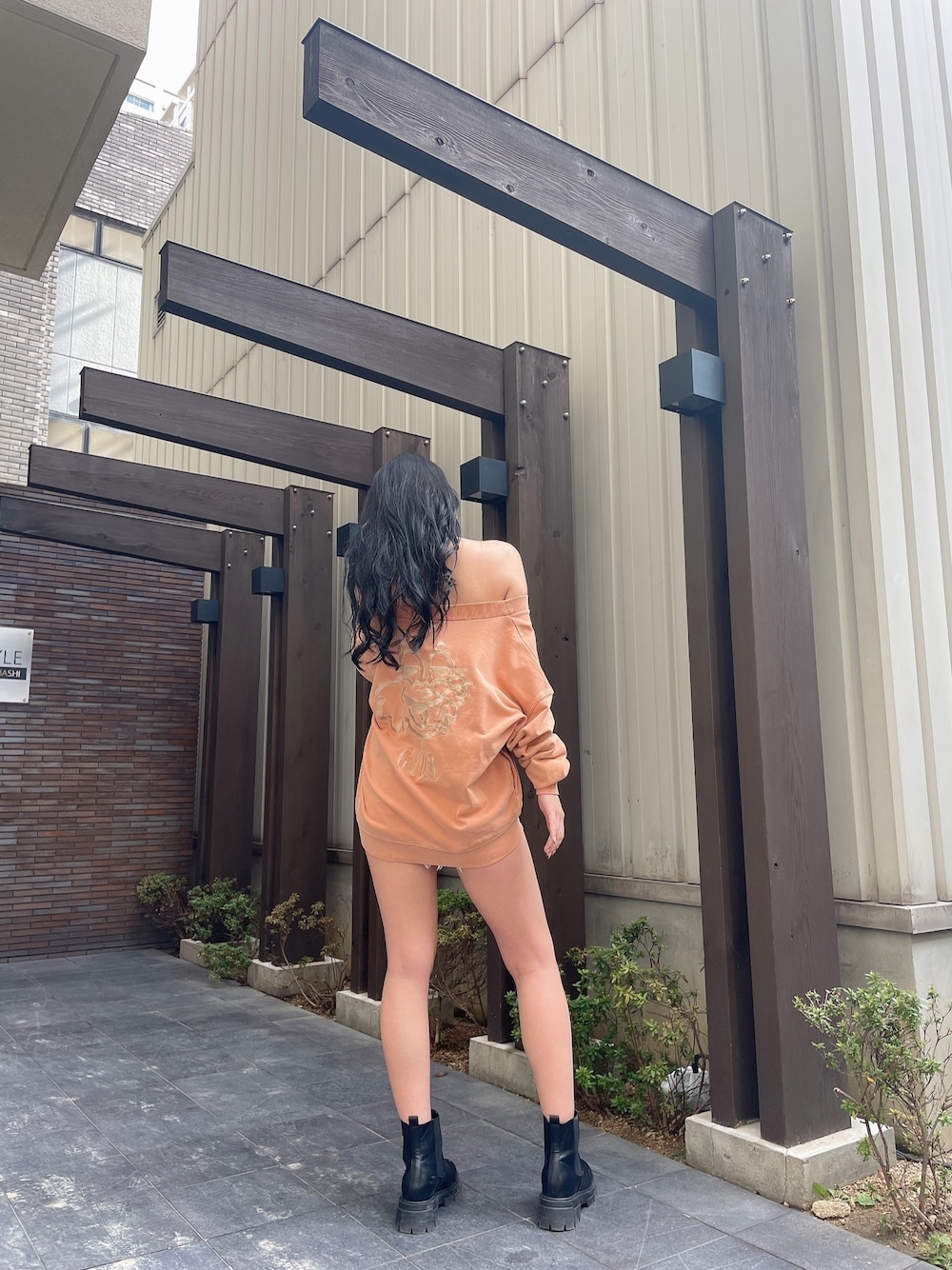 オレンジ系のスウェット、ブルー系のデニムパンツ、ブラック系のブーツを着用したレディースの冬コーディネートの1枚目の写真