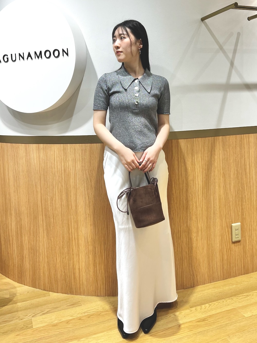 グレー系のニット/セーター、ブラック系のパンプス、ブラウン系のハンドバッグを着用したレディースの春コーディネートの1枚目の写真
