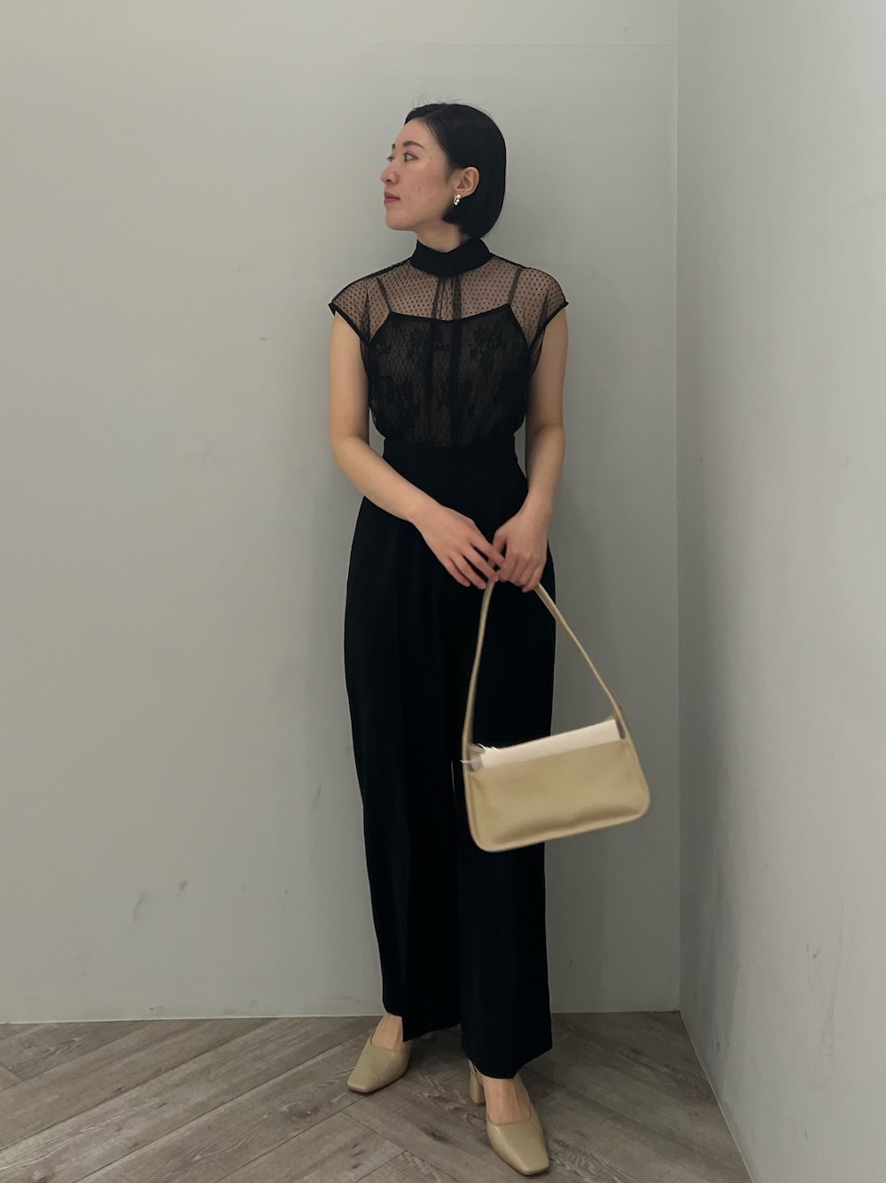 ベージュ系のパンプス、ブラック系のパンツドレス、ベージュ系のハンドバッグを着用したレディースの春コーディネートの1枚目の写真