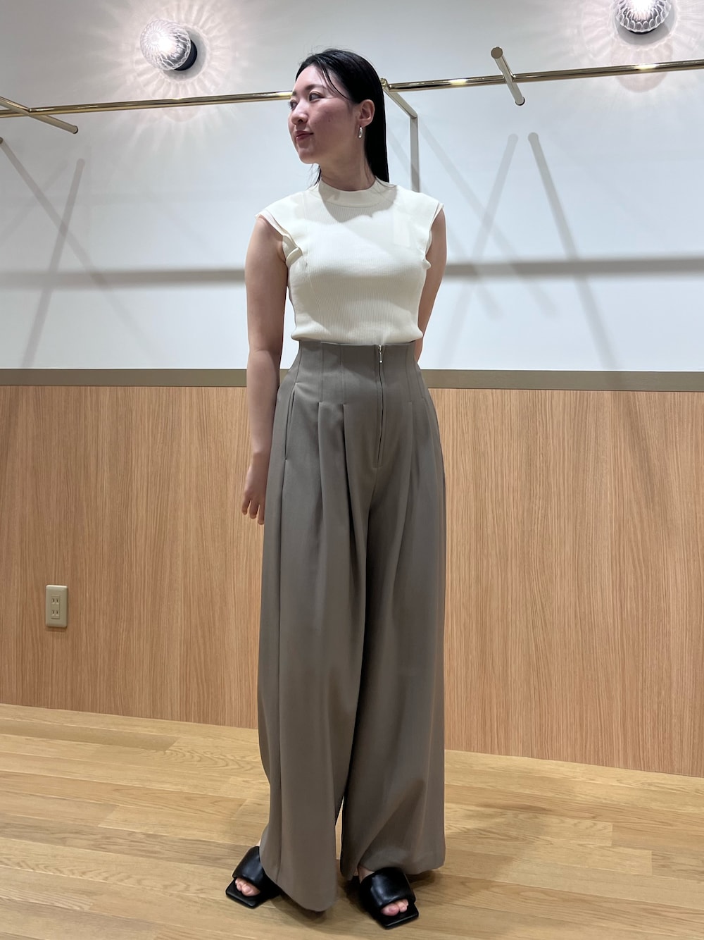 ブラウン系のその他パンツ、ブラック系のサンダル、ホワイト系のニット/セーターを着用したレディースの春コーディネートの1枚目の写真