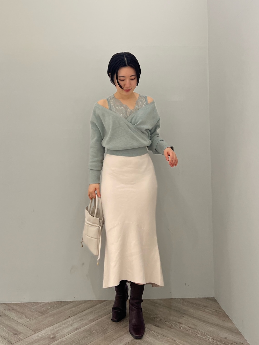 レッド系のブーツ、ホワイト系のハンドバッグ、ホワイト系のスカートを着用したレディースの冬コーディネートの1枚目の写真