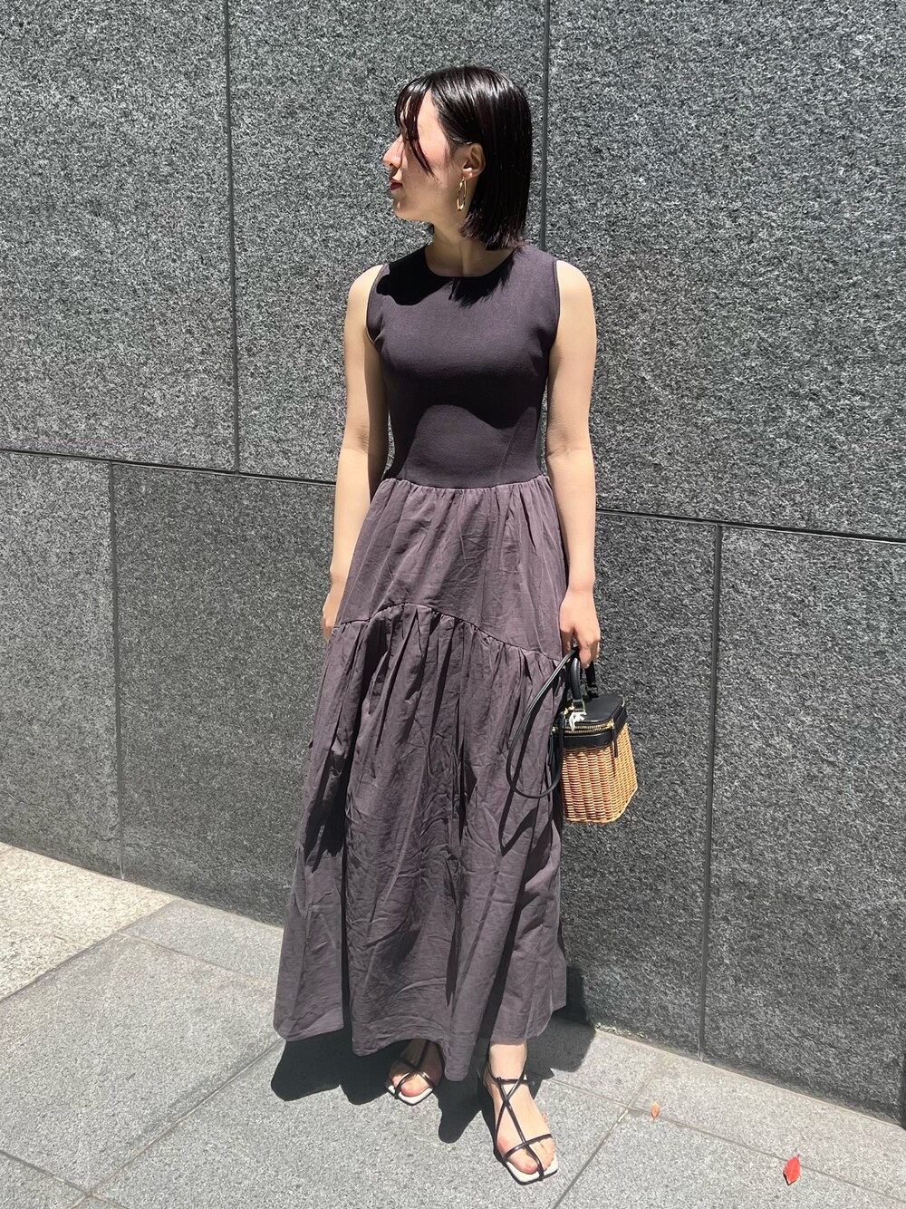 ブラック系のショルダーバッグ、ブラック系のサンダル、グレー系のワンピースを着用したレディースの春コーディネートの1枚目の写真