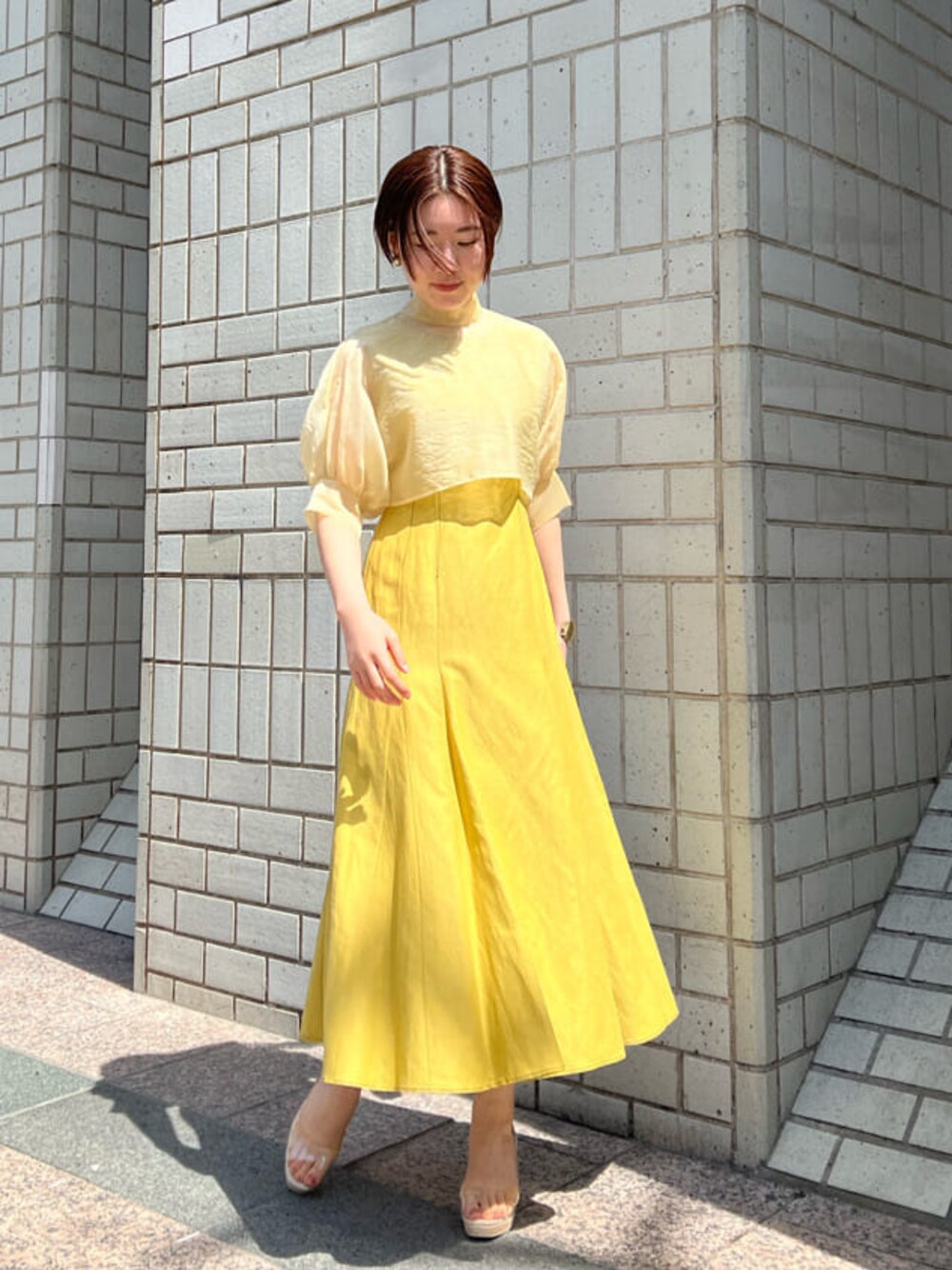 その他のパンプス、イエロー系のワンピース、ゴールド系のバングル/リストバンドを着用したレディースの春コーディネートの1枚目の写真