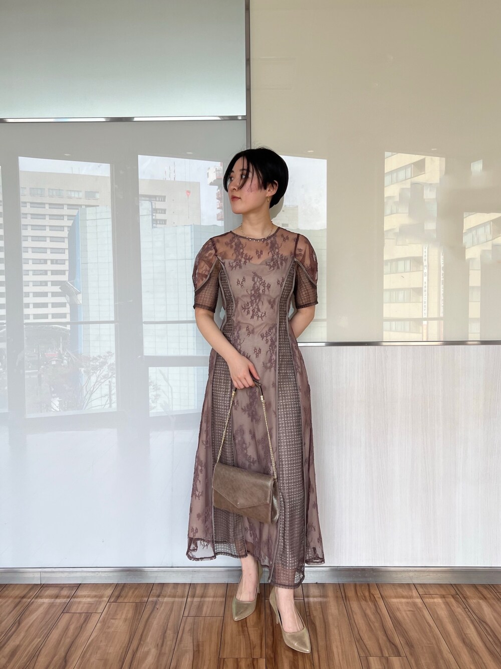 ゴールド系のハンドバッグ、ゴールド系のパンプス、ベージュ系のドレスを着用したレディースの冬コーディネートの1枚目の写真