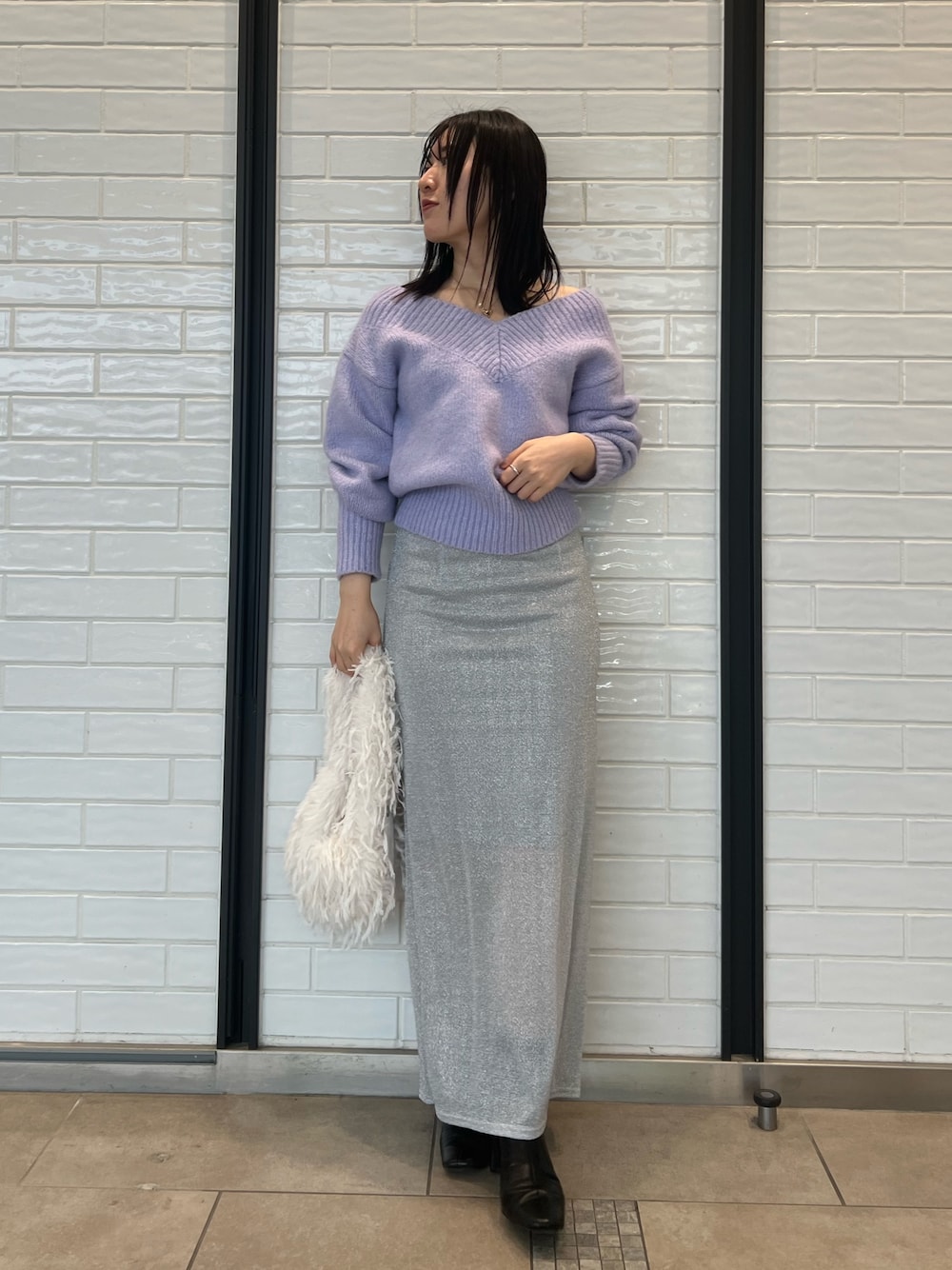 パープル系のニット/セーター、シルバー系のスカートを着用したレディースの冬コーディネートの1枚目の写真
