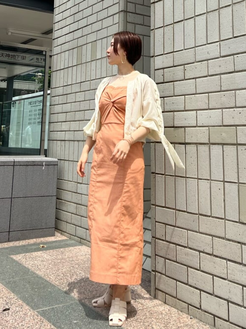 ホワイト系のブルゾン、オレンジ系のワンピース、ホワイト系のサンダルを着用したレディースの春コーディネートの1枚目の写真