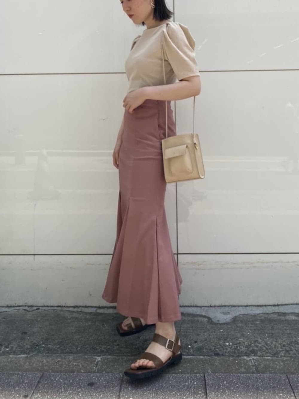 ベージュ系のTシャツ/カットソー、ブラウン系のサンダル、ベージュ系のハンドバッグを着用したレディースの夏コーディネートの1枚目の写真