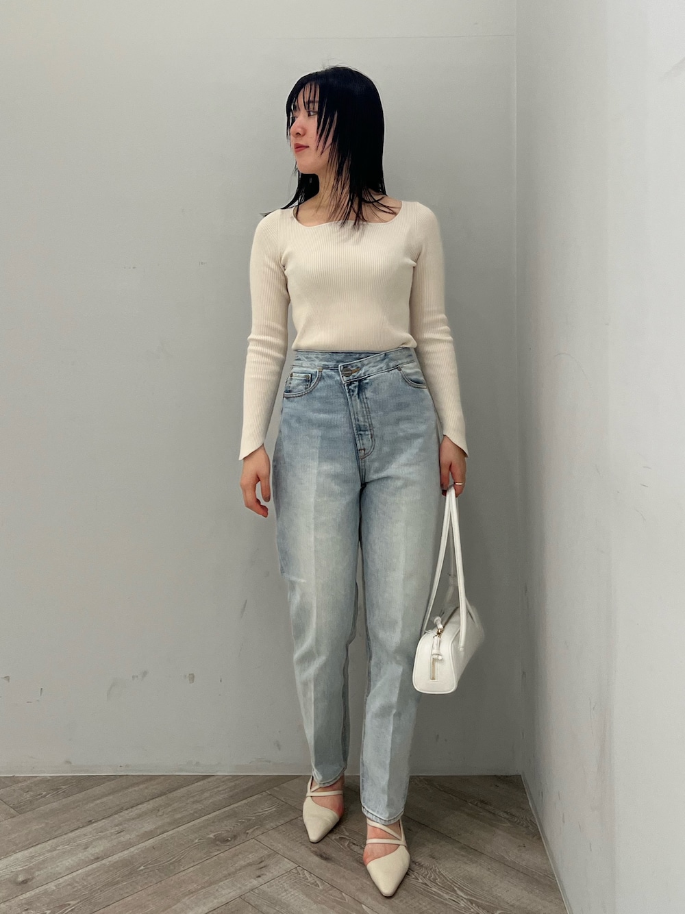ホワイト系のニット/セーター、ブルー系のデニムパンツ、ホワイト系のパンプスを着用したレディースの春コーディネートの1枚目の写真