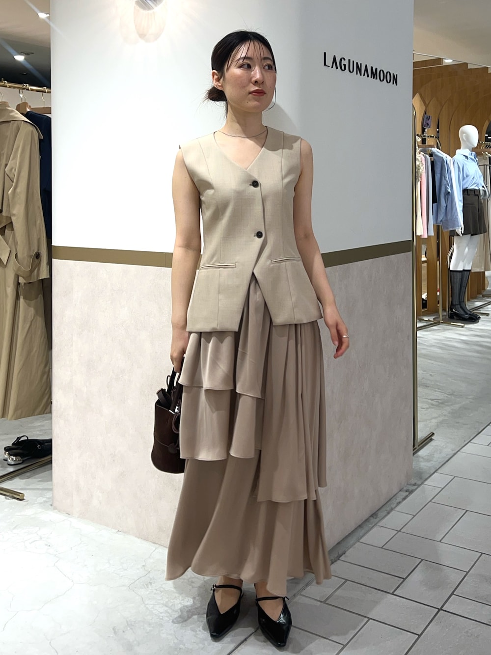 ベージュ系のワンピース、ブラック系のパンプス、ブラウン系のハンドバッグを着用したレディースの春コーディネートの1枚目の写真