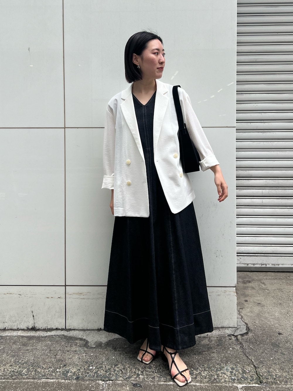 ブラック系のワンピース、ブラック系のサンダル、ブラック系のハンドバッグを着用したレディースの春コーディネートの1枚目の写真