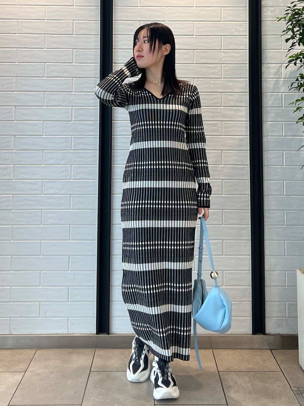 ブルー系のショルダーバッグ、ブラック系のワンピース、グレー系のスニーカーを着用したレディースの冬コーディネートの1枚目の写真