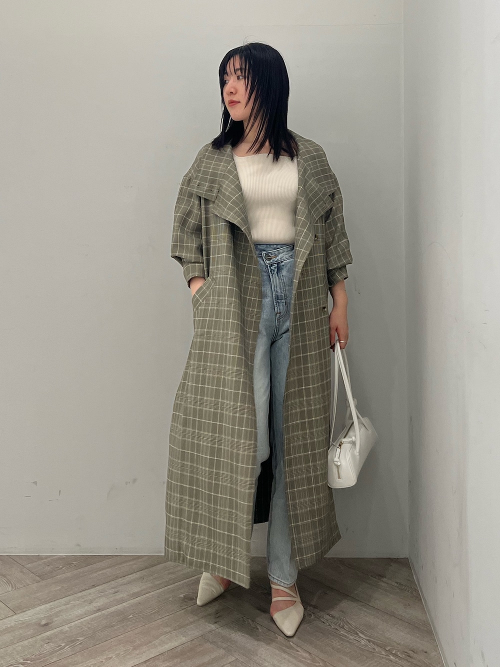 グレー系のチェスターコート、ブルー系のデニムパンツ、ホワイト系のニット/セーターを着用したレディースの春コーディネートの1枚目の写真