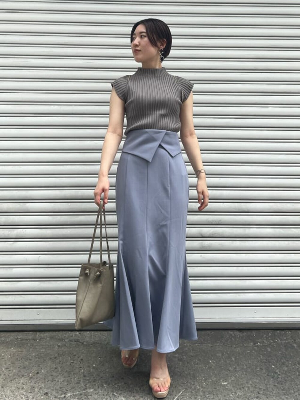 ベージュ系のハンドバッグ、その他のパンプス、ブルー系のスカートを着用したレディースの夏コーディネートの1枚目の写真