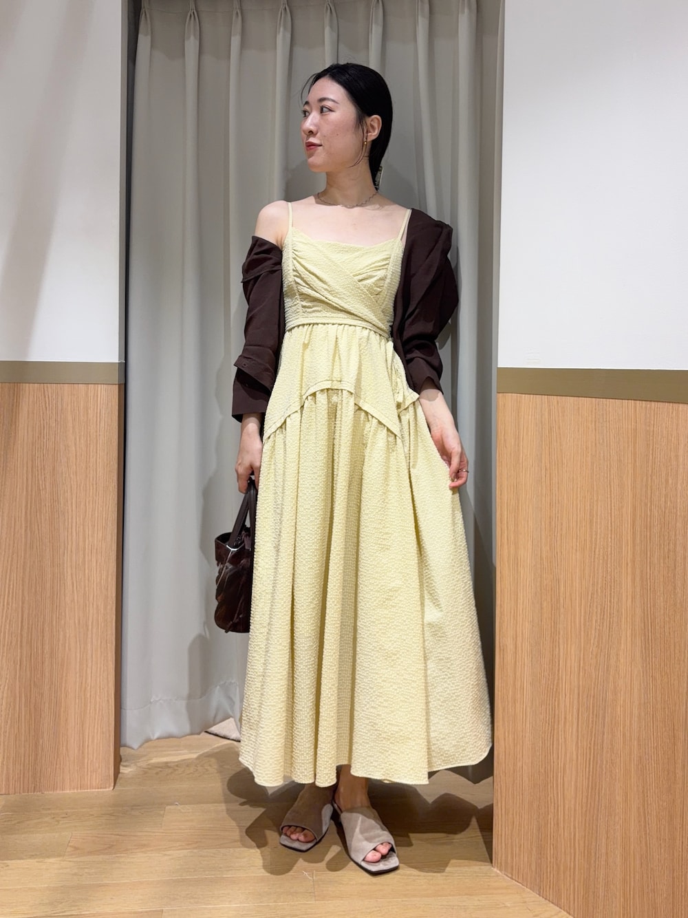 イエロー系のワンピース、ブラウン系のシャツ/ブラウス、ベージュ系のサンダルを着用したレディースの夏コーディネートの1枚目の写真