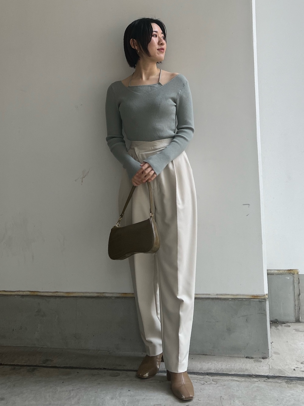 ベージュ系のブーツ、ホワイト系のスラックス、ホワイト系のニット/セーターを着用したレディースの冬コーディネートの1枚目の写真