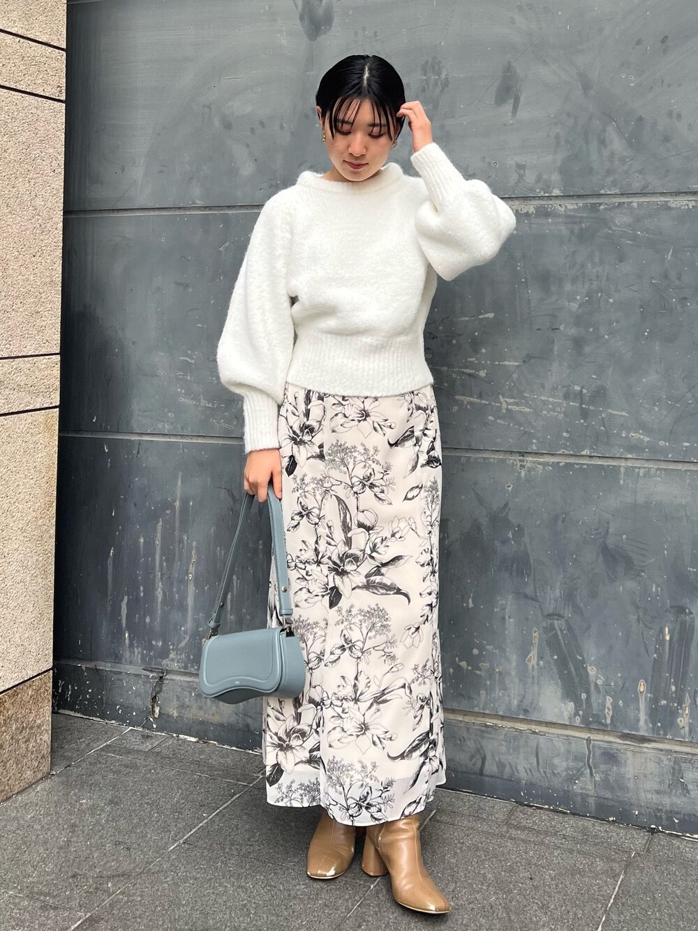 ベージュ系のブーツ、ブルー系のショルダーバッグ、ホワイト系のスカートを着用したレディースの冬コーディネートの1枚目の写真