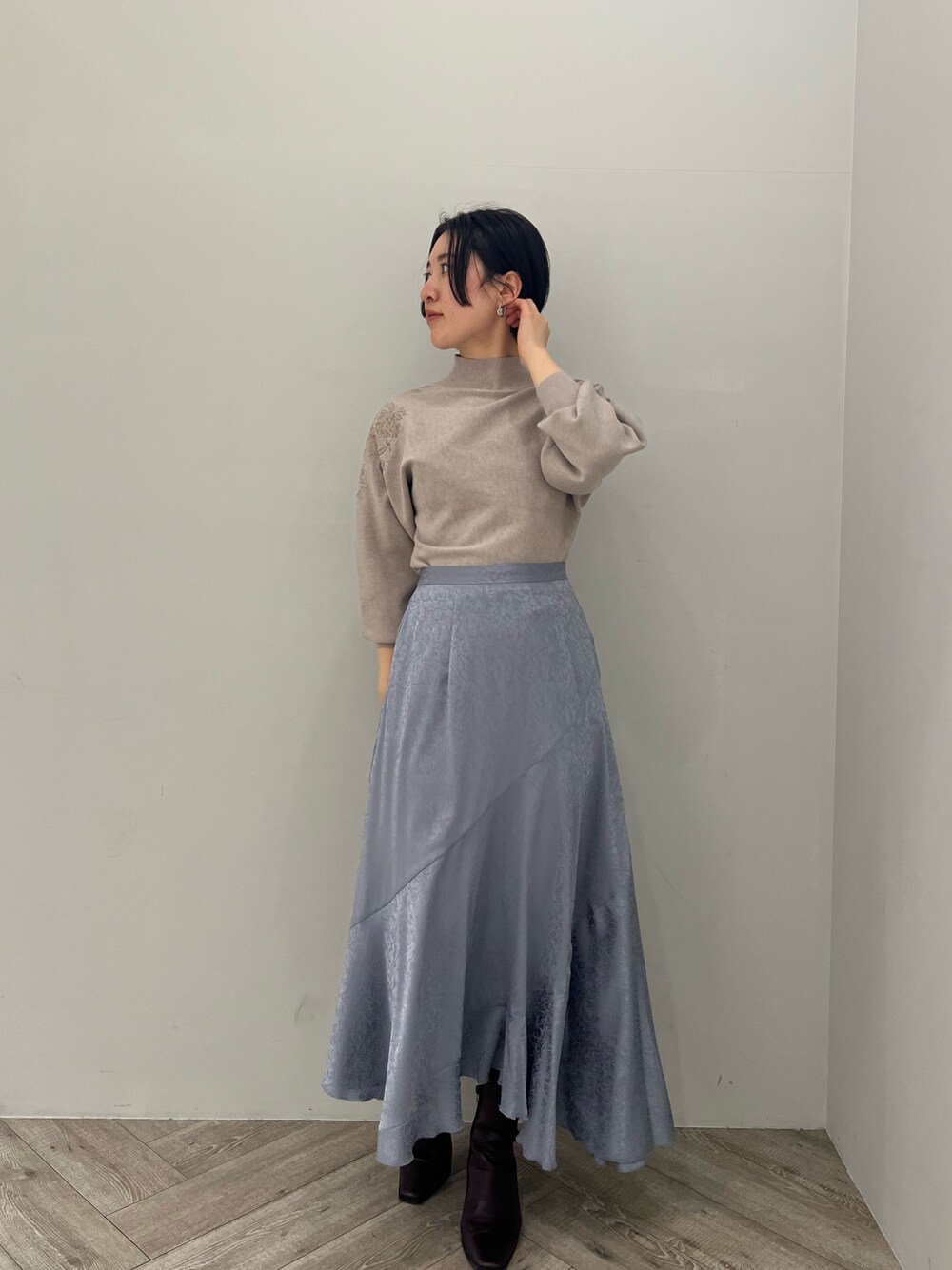 ブルー系のスカート、レッド系のブーツ、グレー系のニット/セーターを着用したレディースの冬コーディネートの1枚目の写真