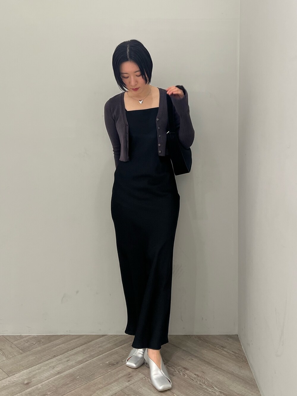 ブラック系のハンドバッグ、シルバー系のパンプス、ブラック系のワンピースを着用したレディースの冬コーディネートの1枚目の写真