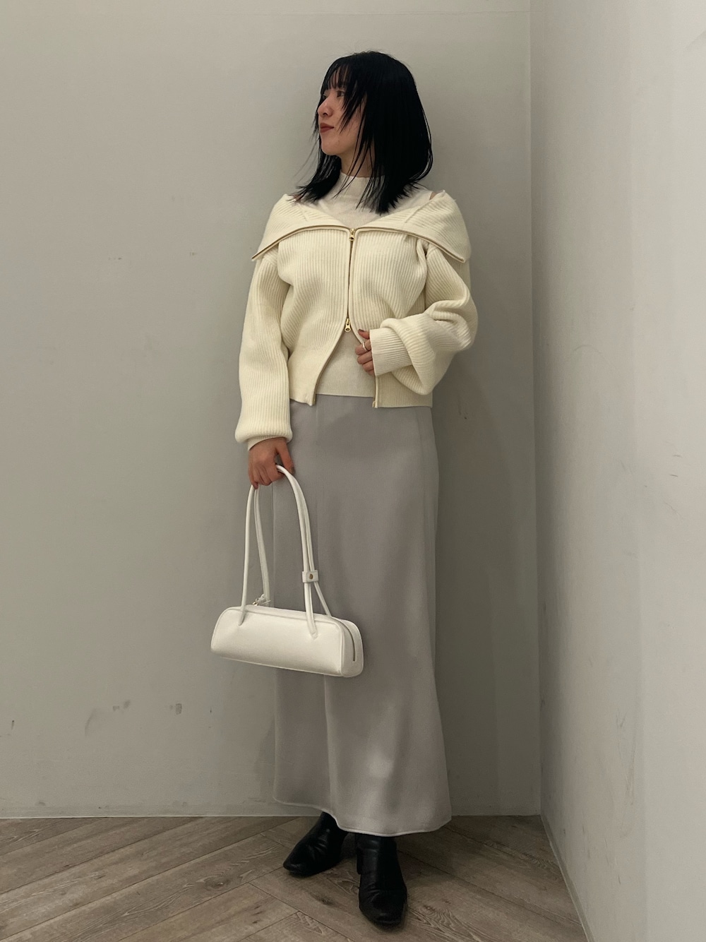 ホワイト系のニット/セーター、グレー系のスカートを着用したレディースの冬コーディネートの1枚目の写真