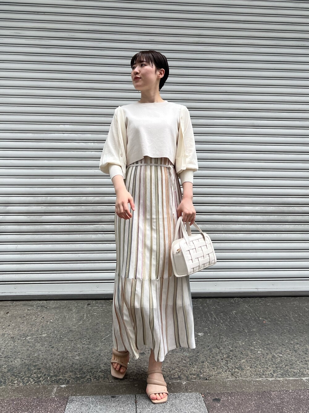 ホワイト系のショルダーバッグ、ベージュ系のサンダル、ホワイト系のワンピースを着用したレディースの春コーディネートの1枚目の写真