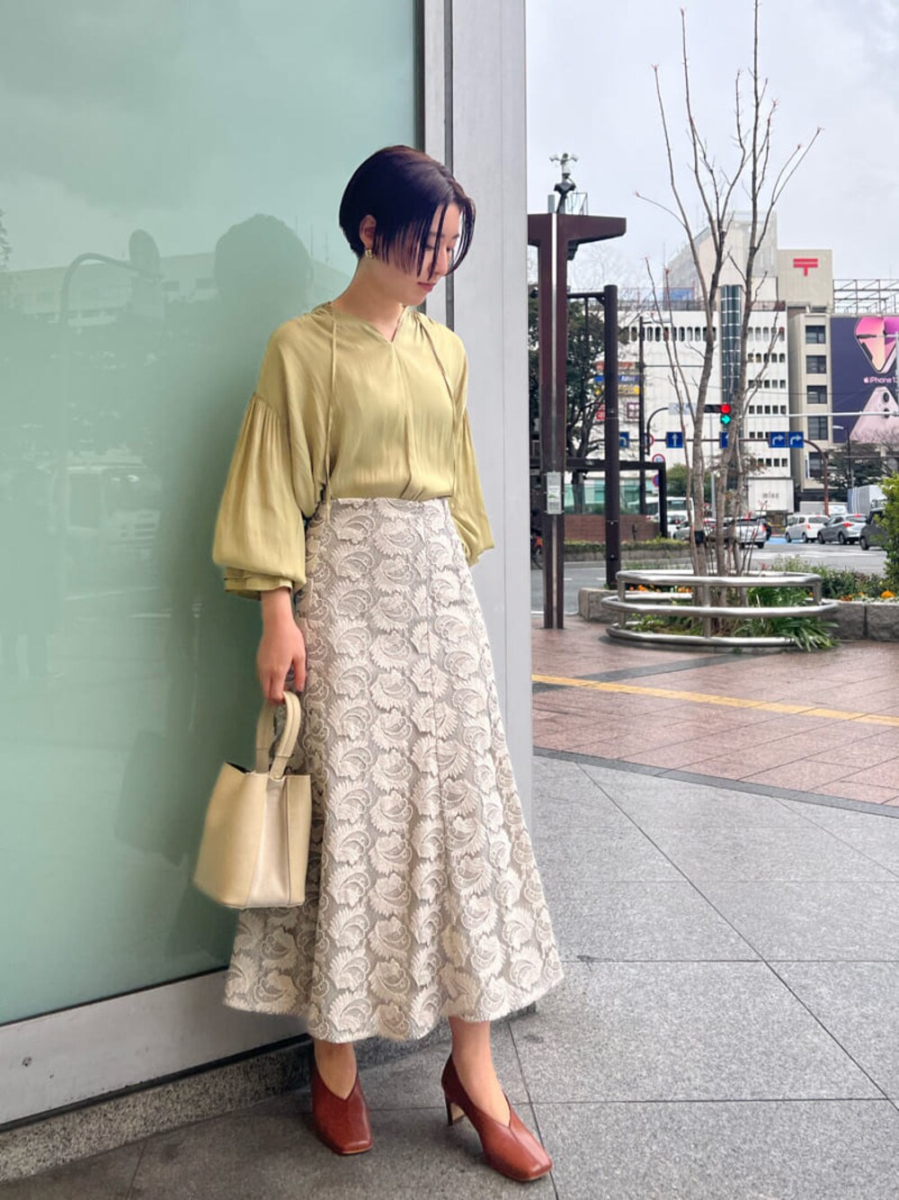 ホワイト系のハンドバッグ、ホワイト系のパンプス、グリーン系のシャツ/ブラウスを着用したレディースの春コーディネートの1枚目の写真