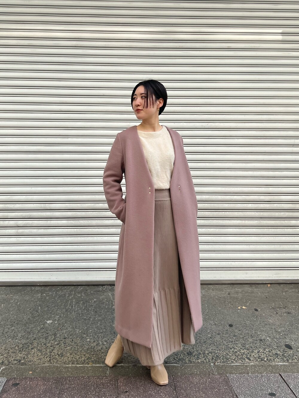 ピンク系のノーカラーコート、ホワイト系のワンピース、ベージュ系のブーツを着用したレディースの秋コーディネートの1枚目の写真