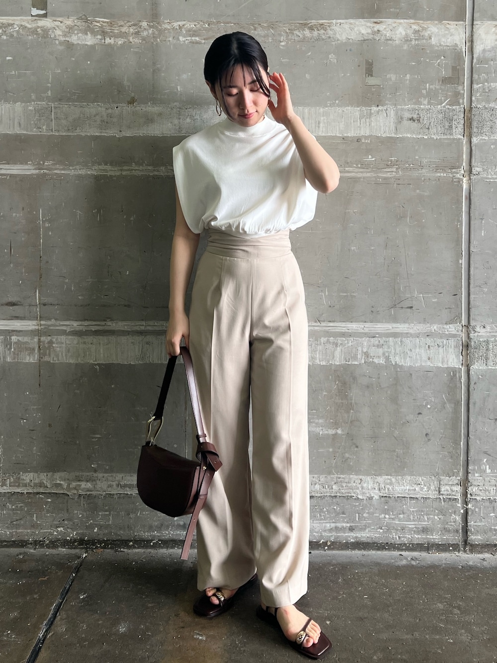 ブラウン系のサンダル、ベージュ系のハンドバッグ、ホワイト系のニット/セーターを着用したレディースの夏コーディネートの1枚目の写真