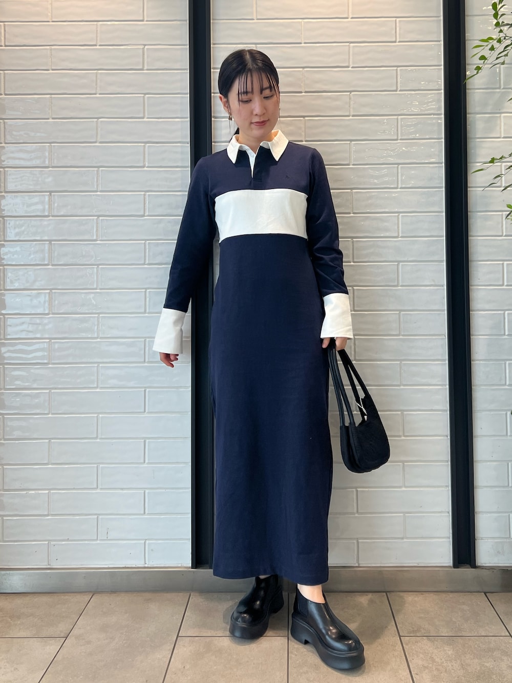 ブラック系のハンドバッグ、ブラック系のブーツ、ブルー系のワンピースを着用したレディースの秋コーディネートの1枚目の写真