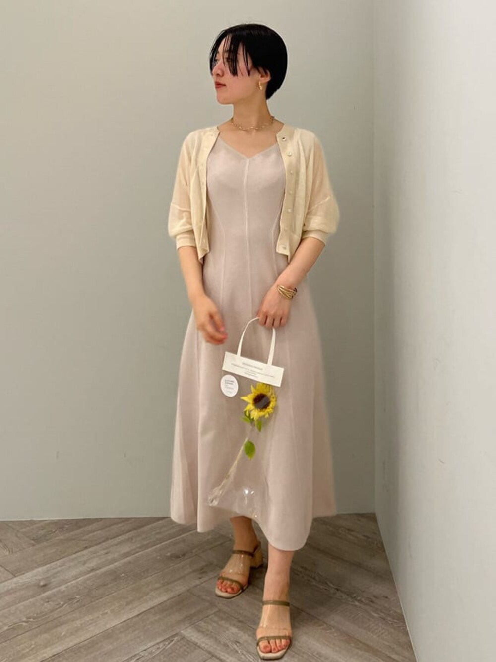 グリーン系のサンダル、ベージュ系のワンピース、ホワイト系のカーディガン/ボレロを着用したレディースの夏コーディネートの1枚目の写真