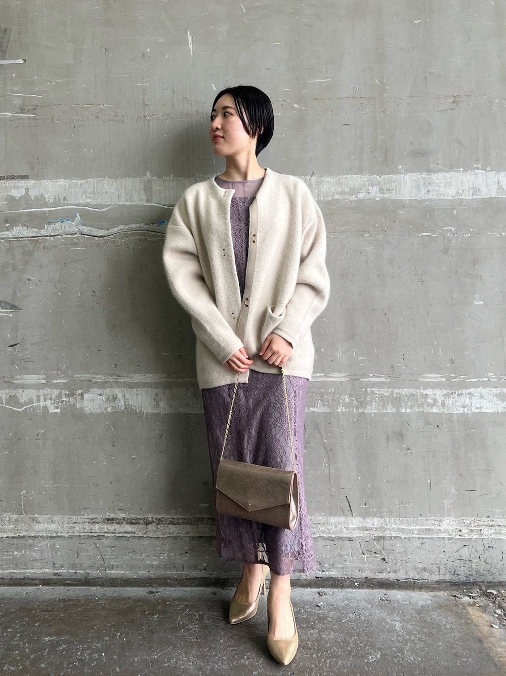ホワイト系のカーディガン/ボレロ、ゴールド系のパンプス、ゴールド系のハンドバッグを着用したレディースの冬コーディネートの1枚目の写真