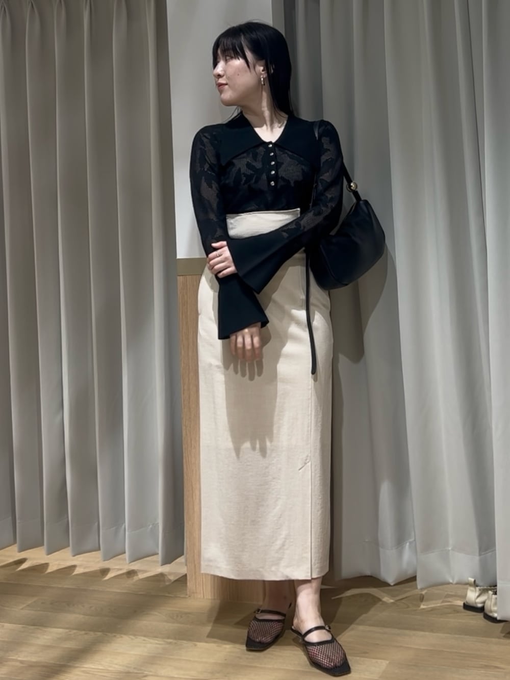 ブラック系のニット/セーター、ベージュ系のスカート、ブラック系のサンダルを着用したレディースの春コーディネートの1枚目の写真