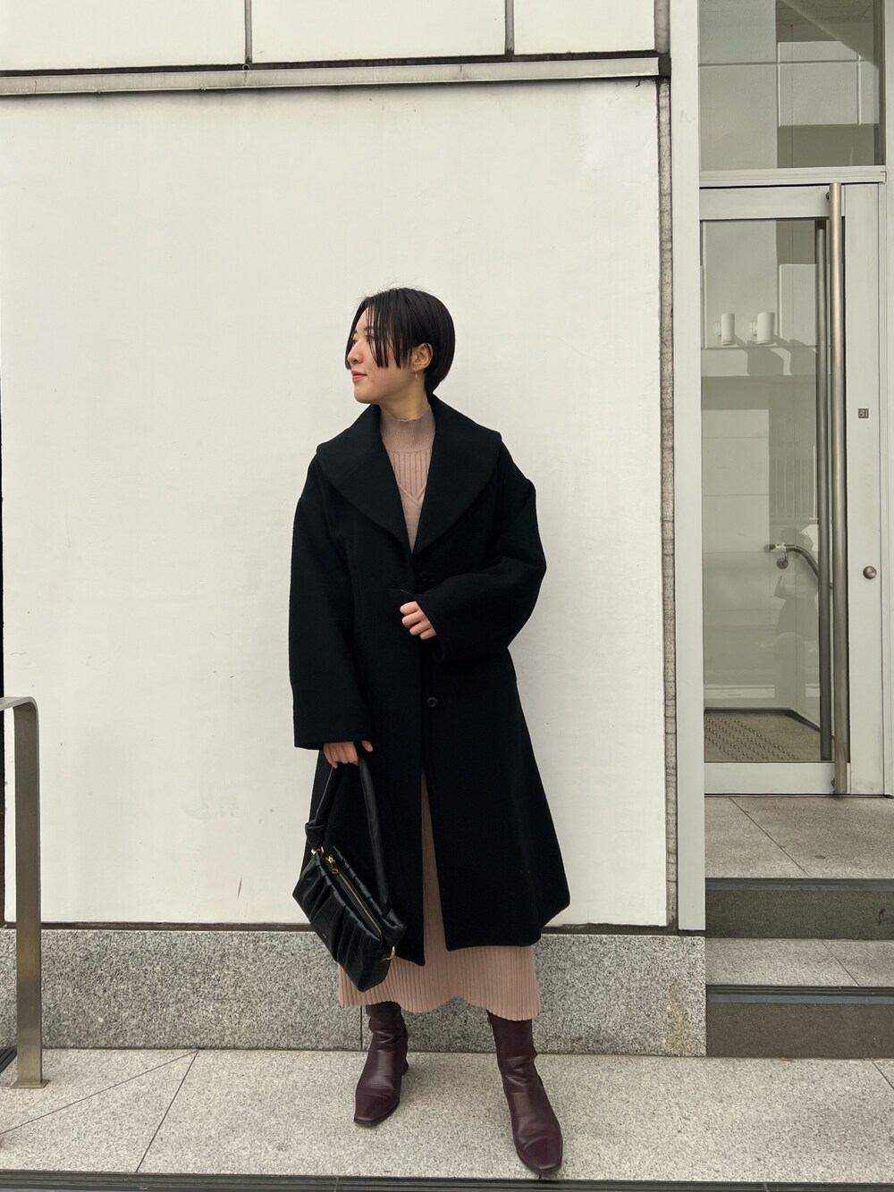 レッド系のブーツ、ブラック系のハンドバッグ、ベージュ系のワンピースを着用したレディースの冬コーディネートの1枚目の写真