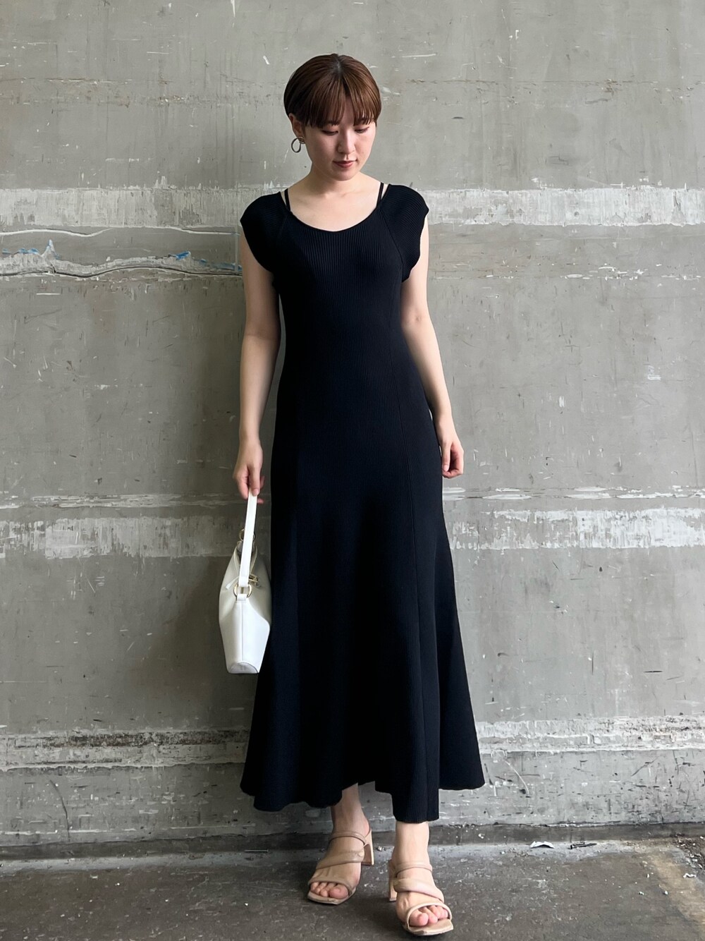 ブラック系のワンピース、ホワイト系のハンドバッグ、ベージュ系のサンダルを着用したレディースの夏コーディネートの1枚目の写真