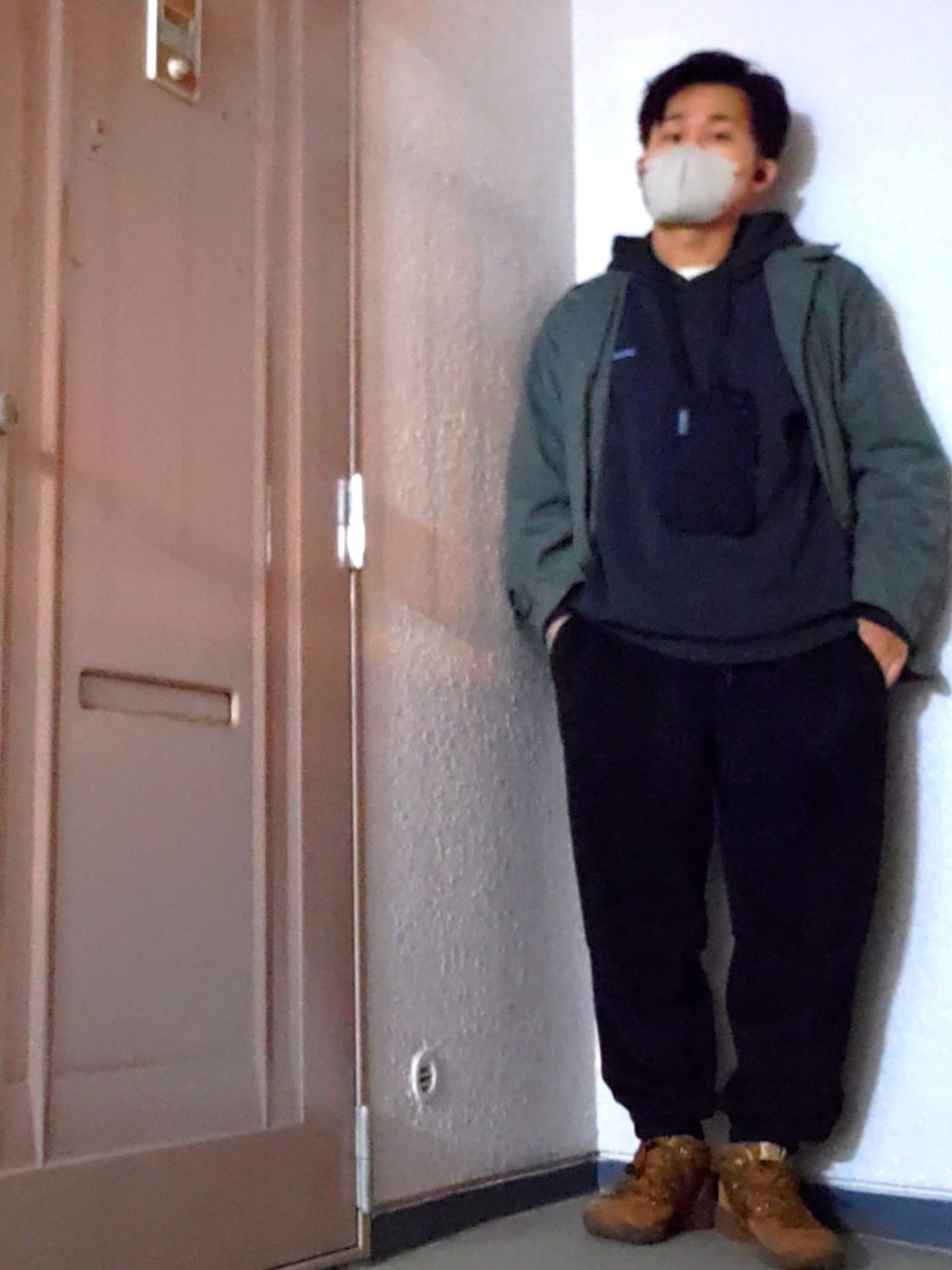 ブラック系のパーカー、グリーン系のミリタリージャケット、ブラック系のスウェットパンツを着用したメンズの冬コーディネートの1枚目の写真