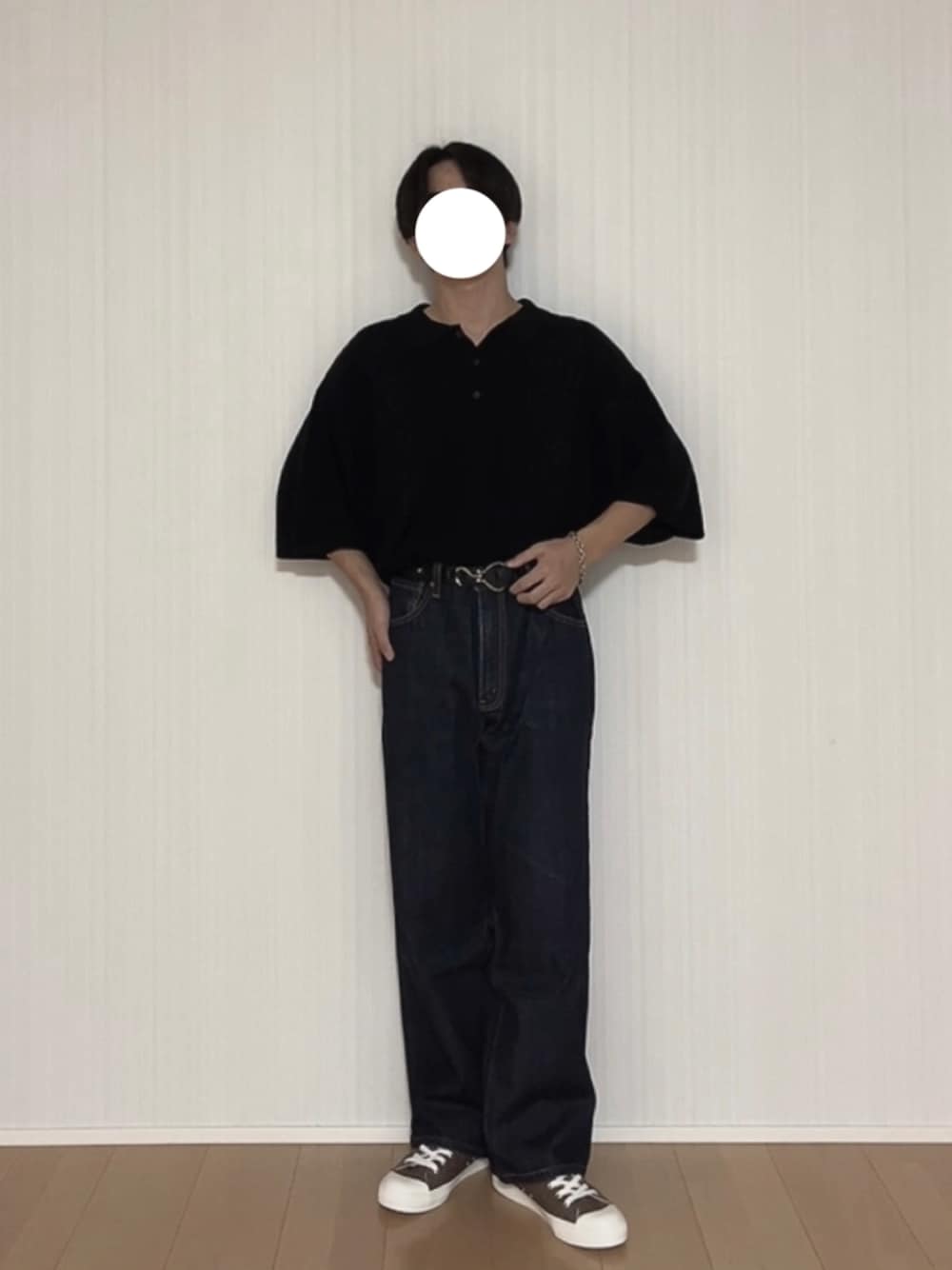 ブラック系のポロシャツ、ブルー系のデニムパンツ、ブラウン系のスニーカーを着用したメンズの秋コーディネートの1枚目の写真