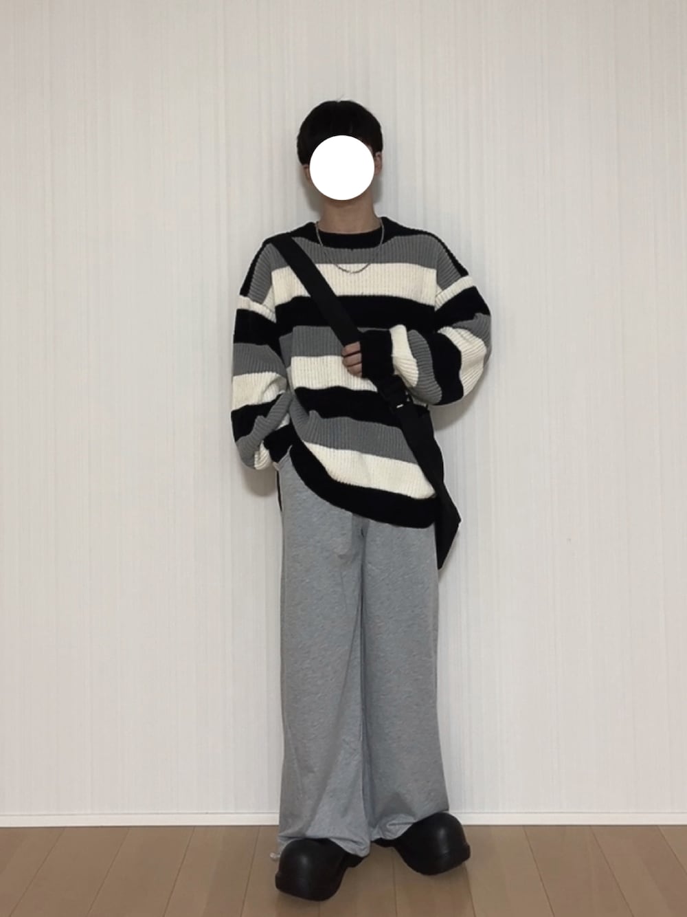 グレー系のスウェットパンツ、ブラック系のスリッポン、ブラック系のニット/セーターを着用したメンズの秋コーディネートの1枚目の写真