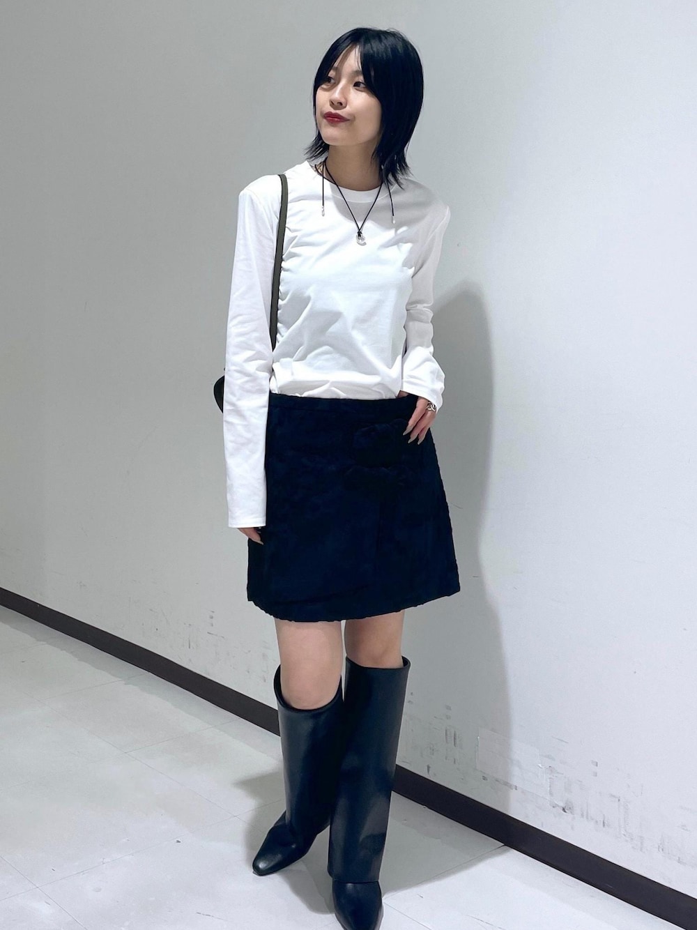 ブラック系のスカート、ブラック系のブーツ、ホワイト系のTシャツ/カットソーを着用したレディースの秋コーディネートの1枚目の写真